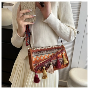 Bohemian crossbody bag featuring colorful knit patterns, long fringe, and a wide strap