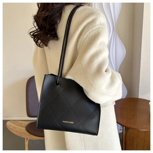 Détail du sac à bandoulière noir matelassé avec lettrage doré et fines bandoulières