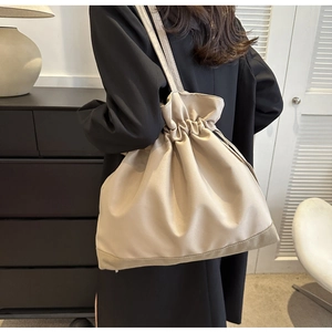 Detailed side view of beige drawstring tote bag showing high capacity and natural drapes