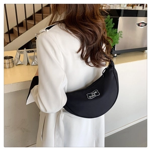 Detail of black nylon crescent moon crossbody bag with YUN QING logo print on white blazer