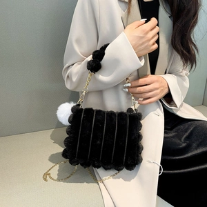 Detail of soft black faux fur shoulder bag with gold chain and white pompom charm