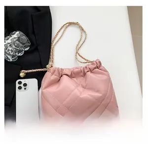 Close-up of pink quilted bucket bag with gold chain and metal logo plate detail