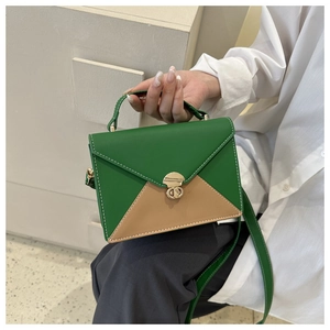 Détail du sac bandoulière vert avec surpiqûres blanches et fermoir doré rotatif