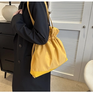 Detailed view of a bright yellow drawstring tote bag with crinkled texture on a model