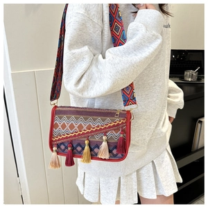 Detail of bohemian ethnic woven shoulder bag featuring colorful tassels and wide strap