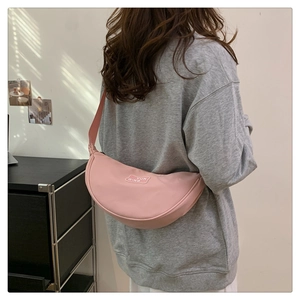 Rear view of pink crescent crossbody bag with branded lettering on a model