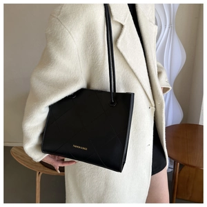 Détail d'un sac à bandoulière matelassé noir chic avec inscription dorée élégante