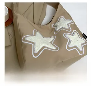 Detail shot of khaki canvas tote featuring plush star patches and fashion label