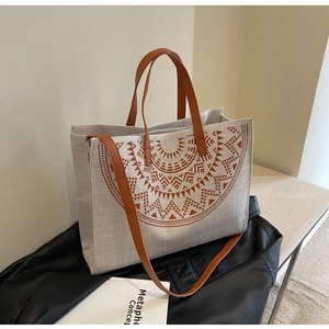 Detailed view of ethnic canvas tote bag showing rustic linen texture and brown leather trim