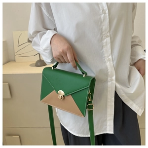 Détail du sac enveloppe vert bicolore avec fermoir rotatif doré et poignée