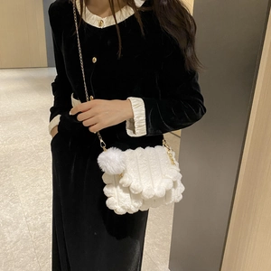Detail of white plush crossbody bag with golden chain strap and soft cloud texture