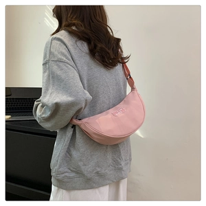 Detailed view of pink nylon half-moon crossbody bag with adjustable strap and brand logo