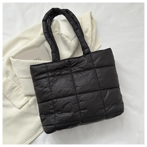 Close-up of black quilted puffer tote bag with premium nylon texture and wide straps