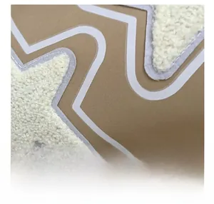 Detail of khaki canvas fabric featuring a white sherpa star patch and embroidery