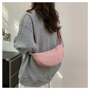 Pink crescent crossbody bag with adjustable strap and YUN QING label shown on model back