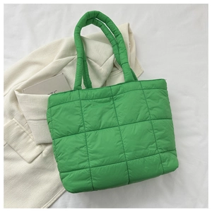 Macro view of bright green quilted tote bag featuring padded nylon texture and square stitching