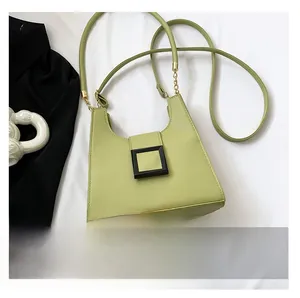 Detail view of light green leather crossbody bag with chain strap and buckle closure