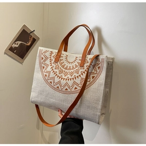 Detail of large canvas tote bag with ethnic print and brown leather handles and strap