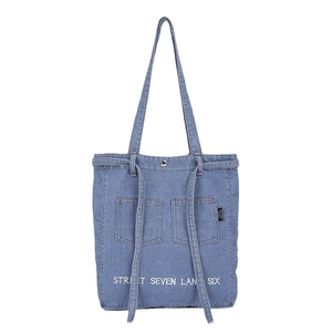 Minimalist denim tote bag in light blue with front pockets and white embroidery detail