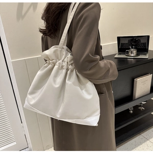 Close-up of a cream white drawstring tote bag in soft faux leather with pleated texture