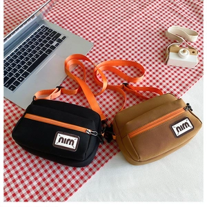 Two small canvas crossbody bags in black and tan with bright orange strap accents