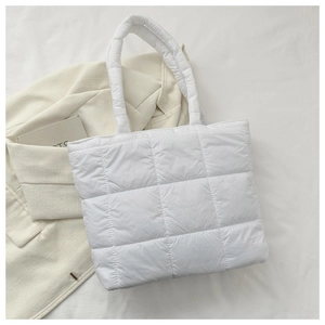 Detail shot of white quilted puffer tote bag showing waterproof texture and soft handles