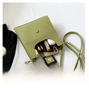 Internal storage of a light green crossbody bag with phone, lipstick and earbuds