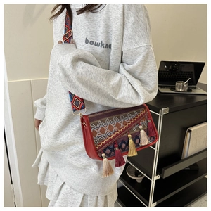 Detail of bohemian red leather crossbody bag with ethnic weave and colorful silk tassels