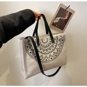 Close-up of beige ethnic canvas tote bag with black geometric pattern and leather handles