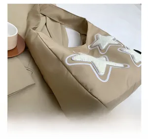 Detail of khaki nylon tote bag featuring white plush star embroidery and premium stitching