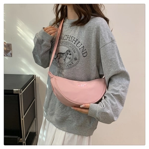 Detail of pink crescent moon crossbody bag with adjustable strap and brand logo patch