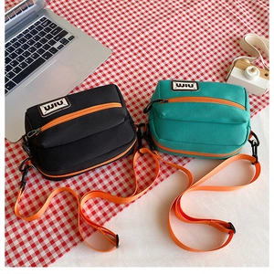 Detail of canvas mini crossbody bags in black and teal with vibrant orange zippers