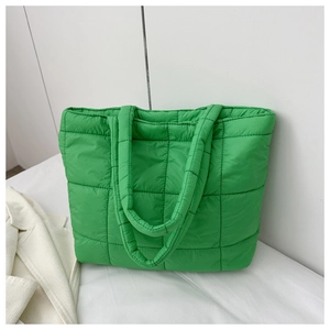 Detail of light green quilted puffer tote bag with soft padded texture and wide shoulder strap