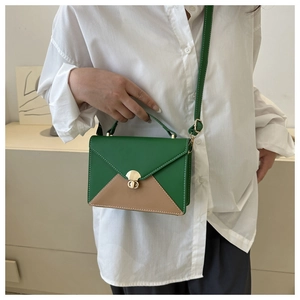 Détail du sac à bandoulière en patchwork vert et marron avec bouton pression doré et coutures
