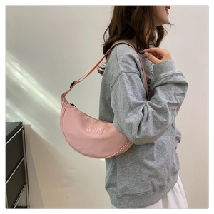 Detail of pink nylon dumpling bag with adjustable strap and YUN QING logo patch