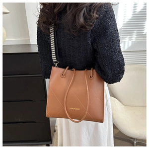Sac bandoulière matelassé marron avec sangle pied-de-poule porté par un mannequin