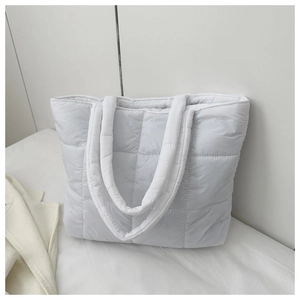 Detail of white quilted puffer tote bag with padded handles and minimalist square stitching