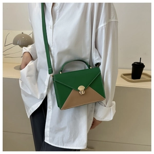 Détail d'un petit sac contrasté vert et marron avec fermoir doré et surpiqûres blanches
