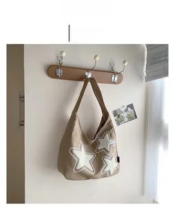 Detail view of khaki canvas tote bag featuring white flocked star patches on a wooden hook