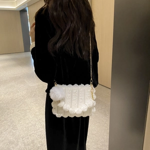 Detail of white plush shoulder bag with vertical stripes and golden chain strap