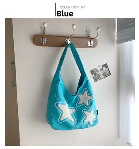 Detail of blue canvas tote bag featuring three white plush star appliques on wood hook