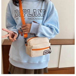 Detail of canvas crossbody bag in beige and orange with adjustable shoulder strap