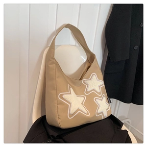Detail of khaki tote bag featuring white plush star patches and fashion label on a chair