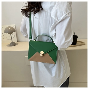 Détail du sac bandoulière en cuir bicolore avec rabat vert et fermoir rotatif en métal
