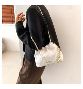 White quilted bucket bag with golden chain strap worn by a model in modern setting