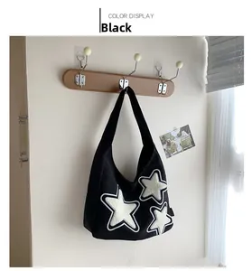 Detail of black canvas tote bag with white plush star patches hanging on a wooden hook