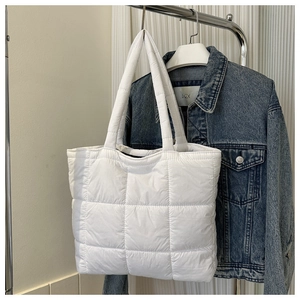 Detailed close-up of white quilted puffer tote bag with classic large square stitching