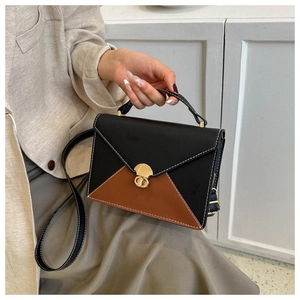 Détail du sac enveloppe bicolore avec serrure dorée rotative et poignée supérieure fine