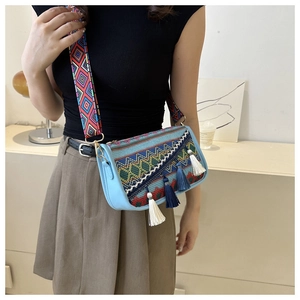 Bohemian blue leather crossbody bag with colorful embroidery and tassels shown on model