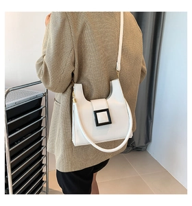 Detailed back view of a white leather crossbody bag with black square buckle on model